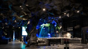 A bar area with a waterfall feature, stone seating, and a bar counter with wine bottles. - La Rock Medellin (Medellín)