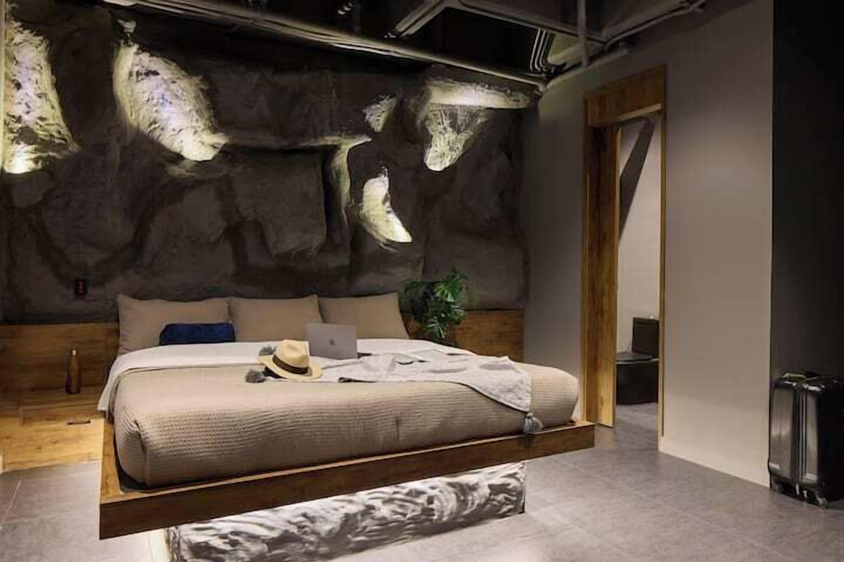 Ein modernes Schlafzimmer mit einem Bett, einem Laptop und einem Koffer.