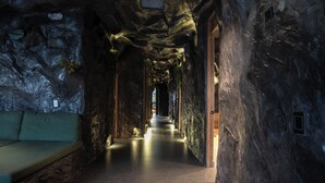 A narrow, dimly lit hallway with a bench on the left and a wooden door at the end. - La Rock Medellin (Medellín)