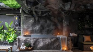 A spa area with a stone bathtub, candles, and a bench. - La Rock Medellin (Medellín)