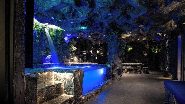 A spa area with a large blue water feature, stone walls, and a bench. - La Rock Medellin (Medellín)