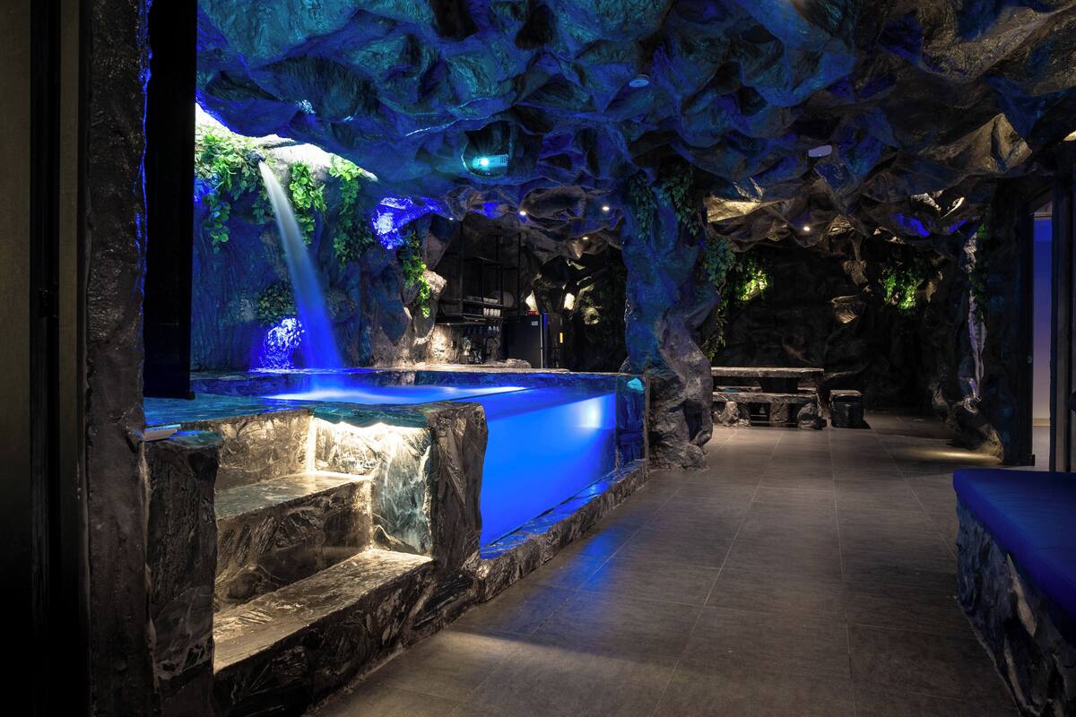 A spa area with a large blue water feature, stone walls, and a bench.