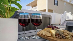 Dos copas de vino sobre una mesa con una tabla de quesos y uvas.