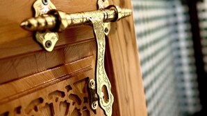 A wooden door with intricate carvings and a brass handle.