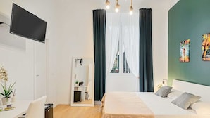 A modern hotel room with a bed, a desk, a TV, and a window with curtains. - Welcome to 5 Terre Central, a newly renovated guest house located in the heart of La Spezia. Our property is the ideal starting point for those who want to explore the wonders of the Cinque Terre, easily reachable thanks to the proximity of the train sta (La Spezia)