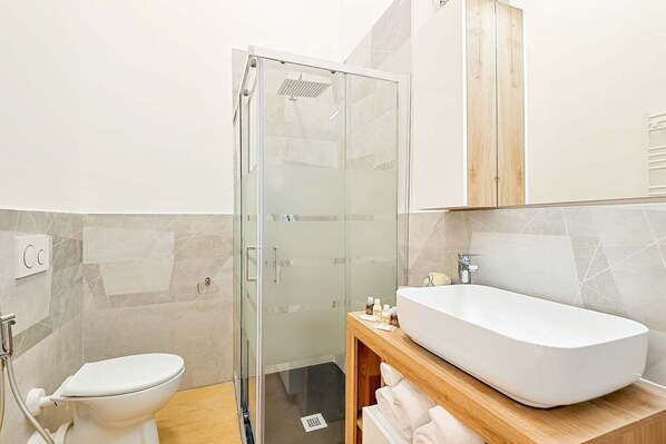 Une salle de bain moderne avec une douche à parois de verre, un lavabo blanc et des toilettes.