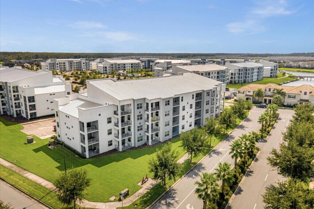 Ett modernt bostadskomplex med flera byggnader, grönskande gräsmattor och fri utsikt  över det omgivande området.