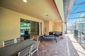 An outdoor patio area with a brick floor, a dining table with chairs, a lounge chair, and a sofa. - Last Minute Disney! Private Pool, Hot Tub, Game Room & Themed Bedrooms. Book Now! #117659 (Orlando)
