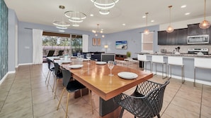 Una cocina moderna con armarios oscuros, una isla grande y un comedor con mesa y sillas de madera.