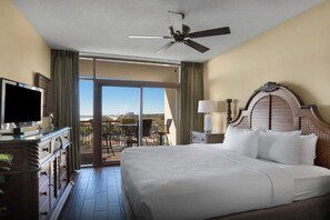 A hotel room with a large bed, a television, a ceiling fan, and a view of the outdoors. - Beachfront Condo | Pools & Swim-Up Bar | Near Golf & Shops (North Myrtle Beach)