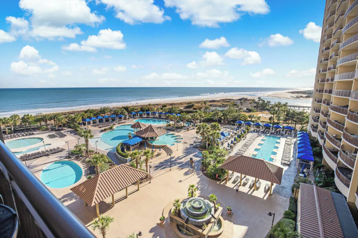 Een resort met meerdere zwembaden, ligbedden en uitzicht op het strand.