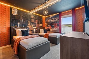 Ein Schlafzimmer mit zwei Betten, einem Bücherregal, einem Schreibtisch und einem großen Fenster.