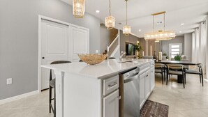 A modern kitchen with a large island, pendant lighting, and a staircase leading to a dining area. - Last Minute Disney Getaway! Private Pool & Themed Bedrooms. Book Now! #150497 (Orlando)