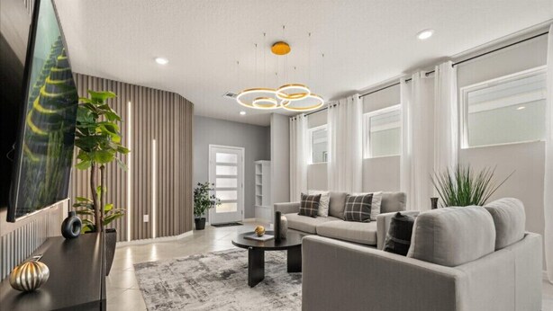 A modern living room with a sofa, coffee table, and a TV. - Last Minute Disney Getaway! Private Pool & Themed Bedrooms. Book Now! #150497 (Orlando)