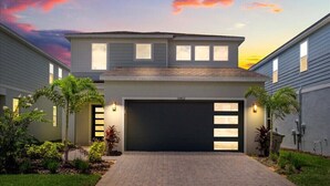 A modern two-story house with a garage, surrounded by a landscaped garden. - Last Minute Disney Getaway! Private Pool & Themed Bedrooms. Book Now! #150497 (Orlando)