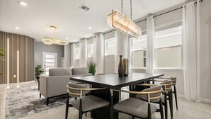 A modern dining area with a rectangular table, six chairs, and a hanging chandelier. - Last Minute Disney Getaway! Private Pool & Themed Bedrooms. Book Now! #150497 (Orlando)