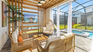 A sunlit room with wicker furniture, a hanging chair, and a view of a pool and ocean. - Last Minute Disney! Private Pool, Hot Tub, Game Room & Themed Bedrooms. Book Now! #150825 (Orlando)