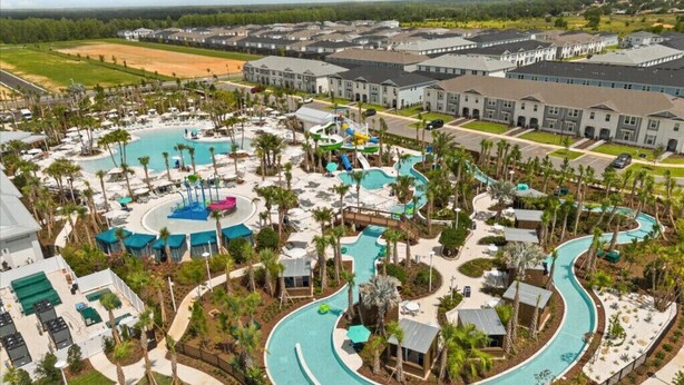 An aerial view of a resort with a large swimming pool, multiple water slides, and a variety of outdoor seating areas surrounded by palm trees. - Last Minute Disney! Private Pool, Hot Tub, Game Room & Themed Bedrooms. Book Now! #150825 (Orlando)