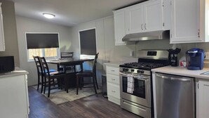 Una cocina compacta con armarios blancos, estufa, horno y cafetera.