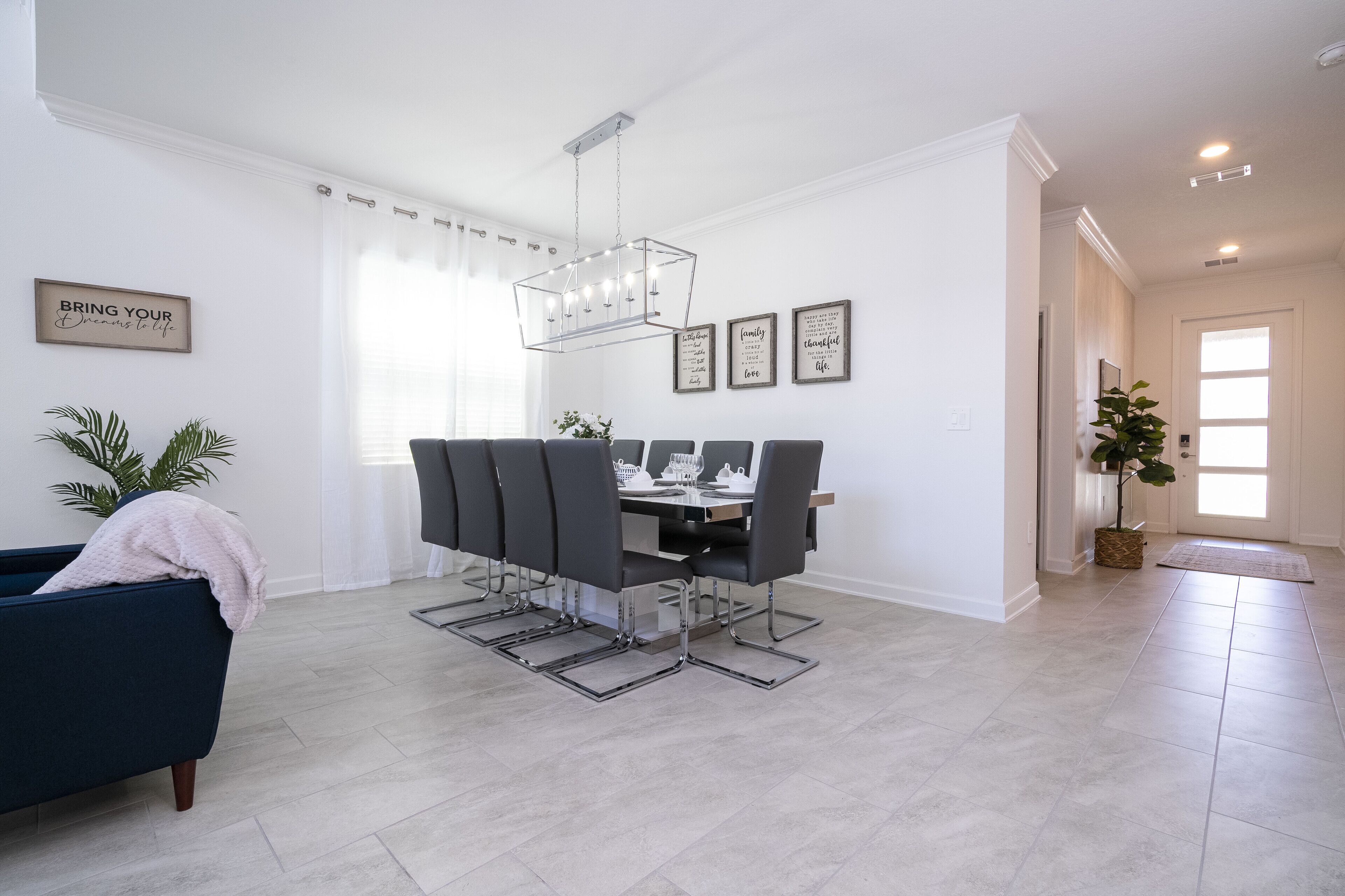 Un espace repas moderne avec une table rectangulaire, des chaises grises et un luminaire suspendu.