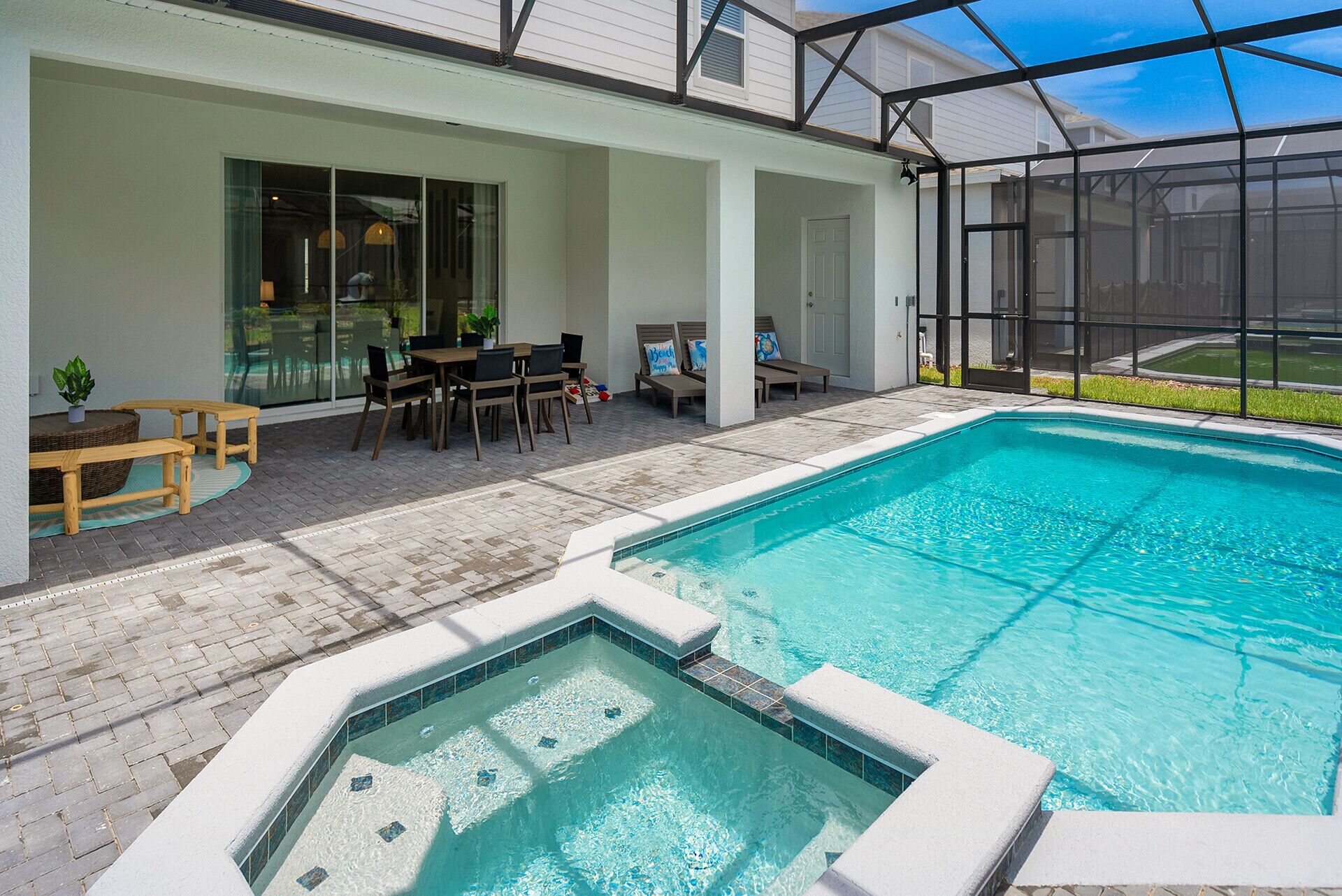 A swimming pool with a hot tub, outdoor seating, and a covered patio area.