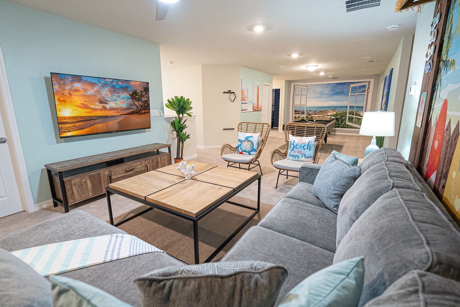 A living room with a sofa, a coffee table, and a TV mounted on the wall.