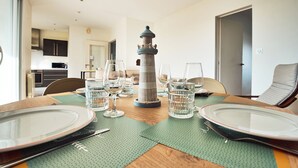 Una mesa de comedor dispuesta con platos, vasos y un centro decorativo con un faro.