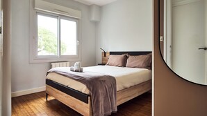 Un dormitorio con cama de madera, una ventana y una puerta.