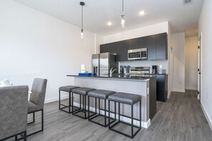 A modern kitchen with a central island, bar stools, and a dining area with chairs. - Last Minute Disney Getaway! Townhouse with themed bedrooms. Book Now! #127367 (Orlando)