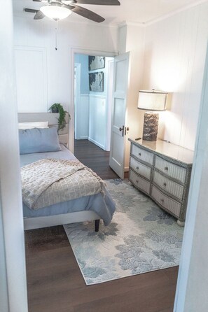 A bedroom with a bed, a dresser, a lamp, and a ceiling fan. - 3BR Emerald Escape /Steps from Beach (Panama City Beach)