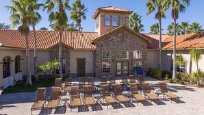 A building with a stone facade, a red-tiled roof, and a covered outdoor seating area with chairs and tables. - Last Minute Disney Getaway! Luxury Condo with Private Balcony. Book Now! #127373 (Orlando)