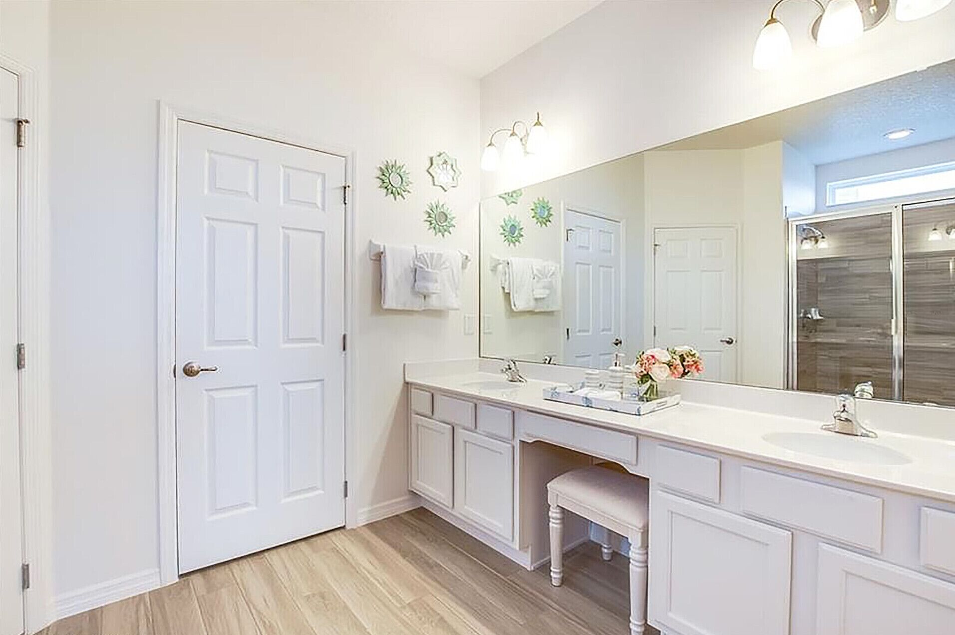 A bathroom with a white vanity, a large mirror, and a shower area.