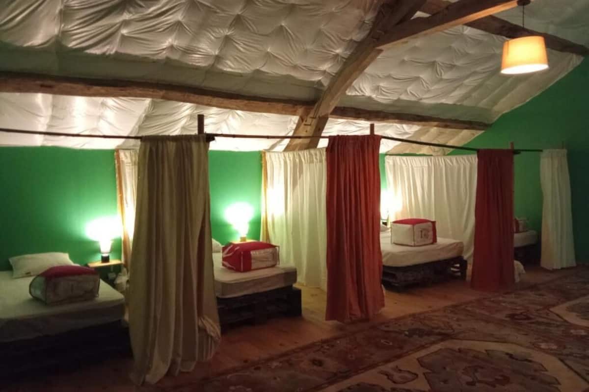 A room with four beds, each with a canopy, and a green wall.