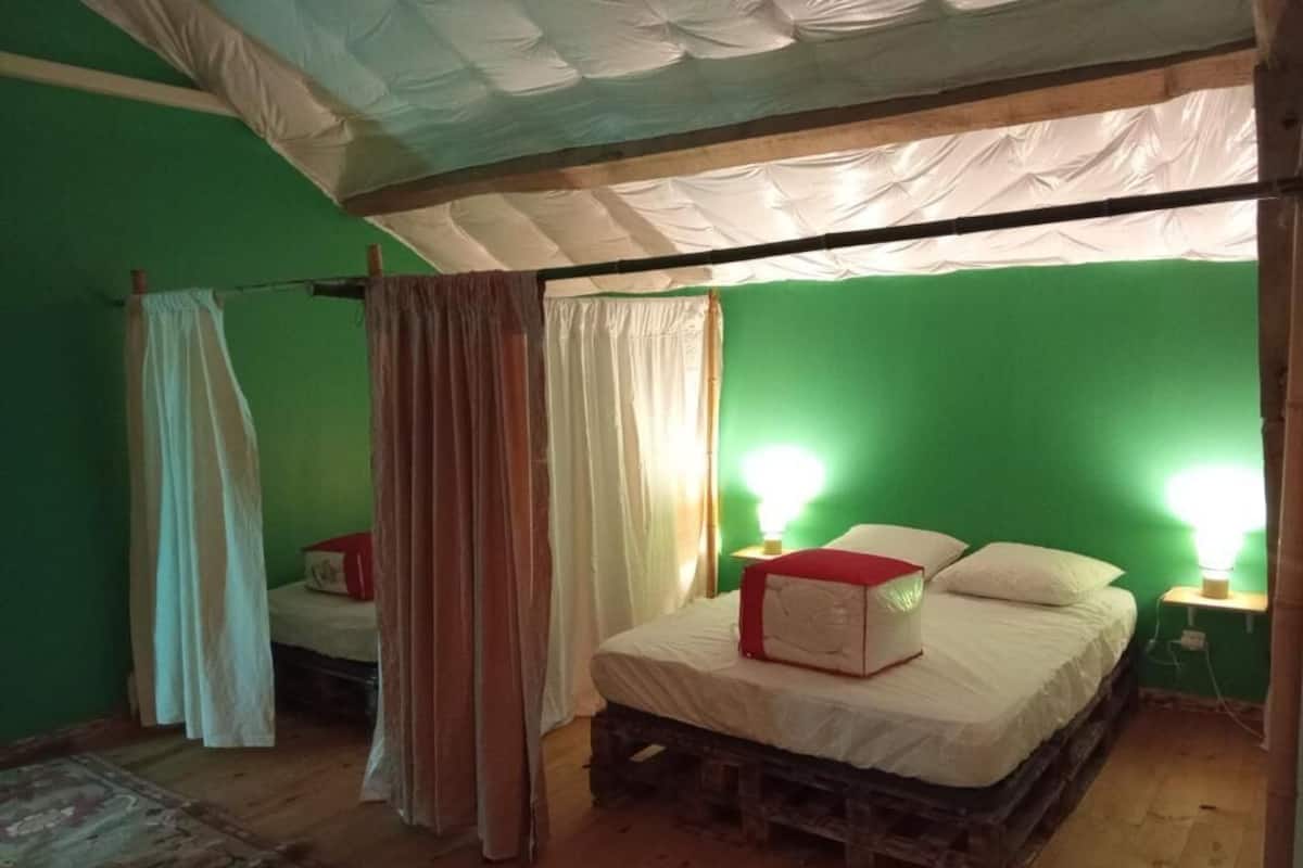 A room with a green wall, a wooden bed, a white canopy, and a red object on the bed.