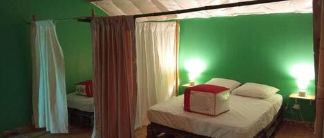 Una habitación con pared verde, cama de madera, dosel blanco y un objeto rojo sobre la cama.