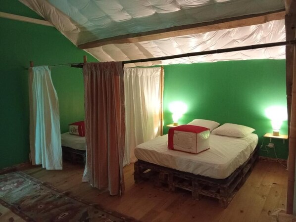 Une pièce avec un mur vert, un lit en bois, un baldaquin blanc et un objet rouge posé sur le lit.