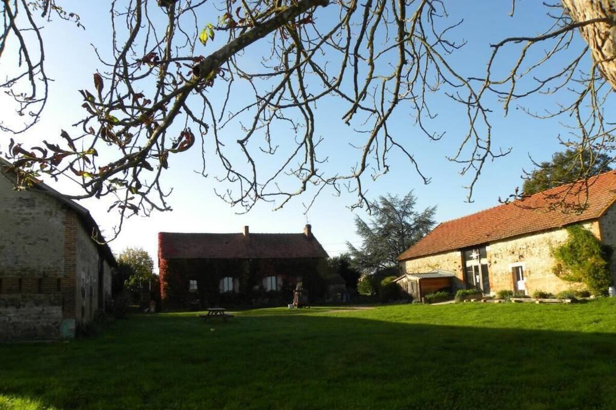 A courtyard with a grassy lawn, a brick building, and a stone building with a red roof.