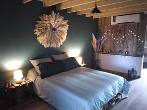 Une chambre à coucher comprenant un lit, des lampes de chevet, un élément décoratif mural et un climatiseur fixé au mur.