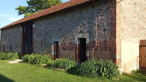 Ein rustikales Steinhaus mit rotem Ziegeldach, einer Holztür und einem kleinen Fenster.