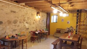 Ein rustikaler Essbereich mit Holztischen und -stühlen, einer Steinwand und einer gelben Akzentwand.