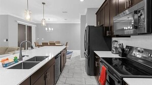 A modern kitchen with a black refrigerator, stainless steel appliances, and a white countertop. - Last Minute Disney Getaway! Townhouse with Private Pool. Book Now! #149357 (Orlando)