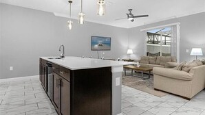 A modern kitchen with a central island, a dining area with a sofa, and a ceiling fan. - Last Minute Disney Getaway! Townhouse with Private Pool. Book Now! #149357 (Orlando)