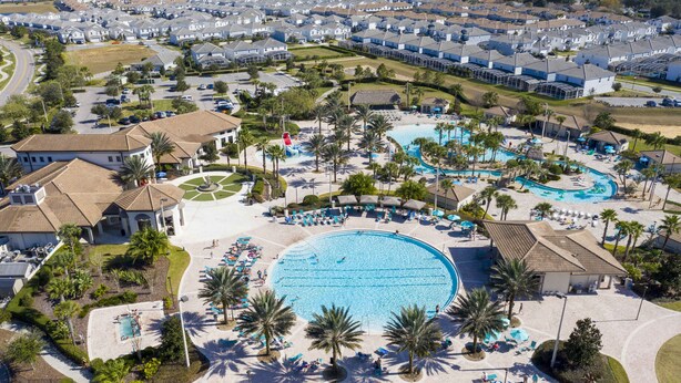 An aerial view of a resort with a large central pool, multiple smaller pools, and a variety of sun loungers and umbrellas. - Last Minute Disney Getaway! Luxury Villa with Private Pool & Hot Tub. Book Now! #150985 (Orlando)