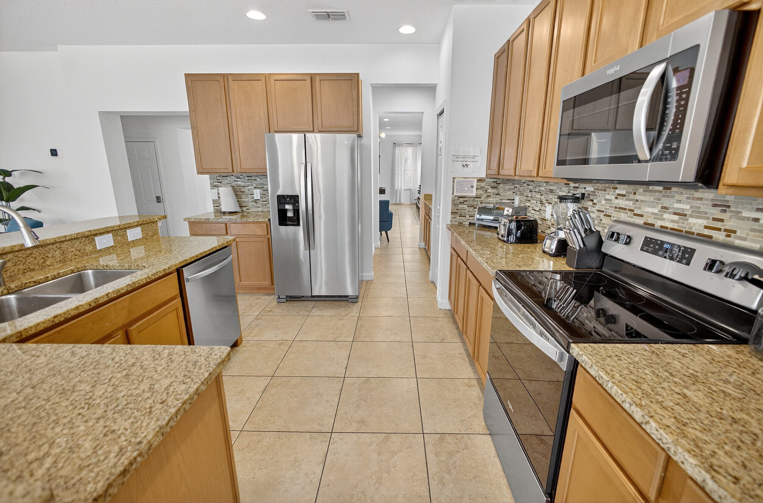 A modern kitchen with granite countertops, stainless steel appliances, and wooden cabinets.