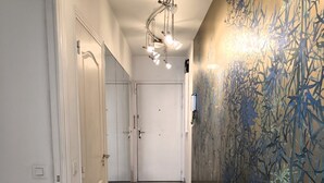 A hallway with a marble floor, white doors, and a wall with a bamboo mural. - Charming three-room beachfront apartment with stunning sea views in the heart of Menton (Menton)