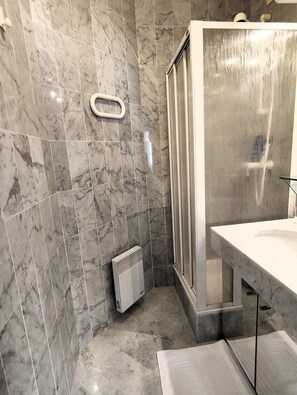A bathroom with marble walls, a shower enclosure, and a white sink. - Charming 3-room apartment on the waterfront with a splendid ocean view in the heart of Menton (Menton)