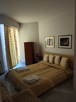 A bedroom with a bed, a wardrobe, and two framed pictures on the wall. - Charming 3-room apartment on the waterfront with a splendid ocean view in the heart of Menton (Menton)