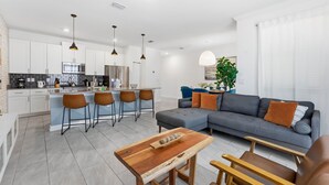 A modern living space with a kitchen, dining area, and a gray sofa with orange cushions. - Last Minute Disney Getaway! Townhouse with Private Pool. Book Now! #160151 (Orlando)