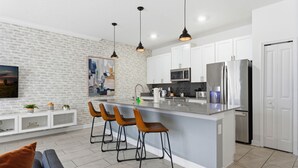 A modern kitchen with a central island, white cabinets, stainless steel appliances, and pendant lighting. - Last Minute Disney Getaway! Townhouse with Private Pool. Book Now! #160151 (Orlando)