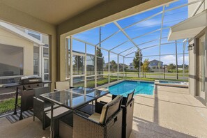 Eine überdachte Terrasse mit Glasveranda, einem Pool, Gartenmöbeln und einem Grill.